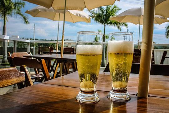 two glasses of beer sitting on a wooden table at Hotel Portal das Águas in Jaguariúna