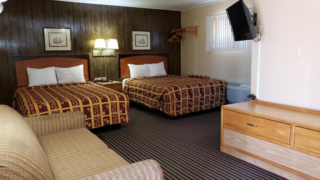 een hotelkamer met 2 bedden en een bank bij Grand Motel in Hastings