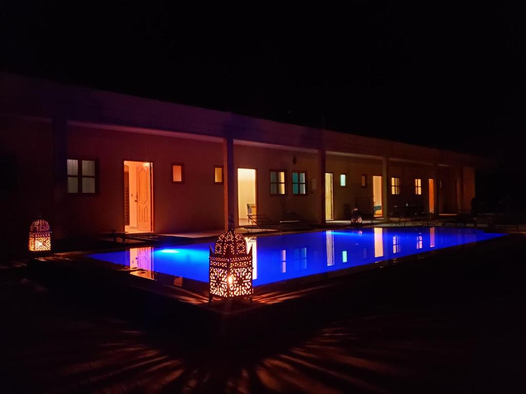 a pool with blue lights in front of a building at night at Riad Hotel Les Flamants in Merzouga