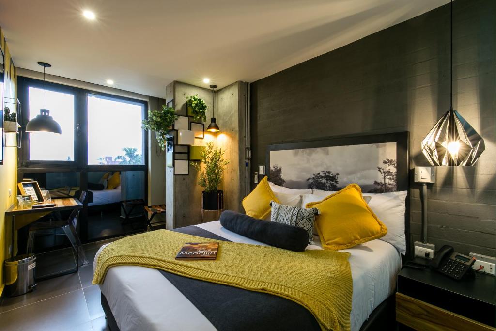 1 dormitorio con 1 cama grande con almohadas amarillas en Epic Boutique Hotel en Medellín