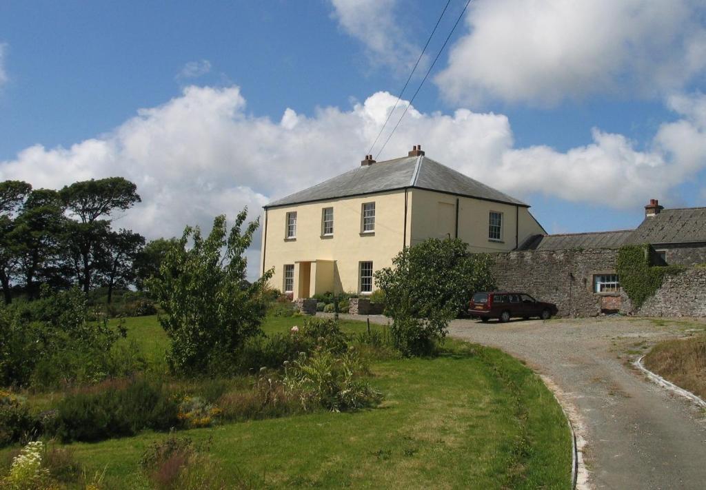 una casa bianca con una macchina parcheggiata di fronte di Lamphey Park a Lamphey