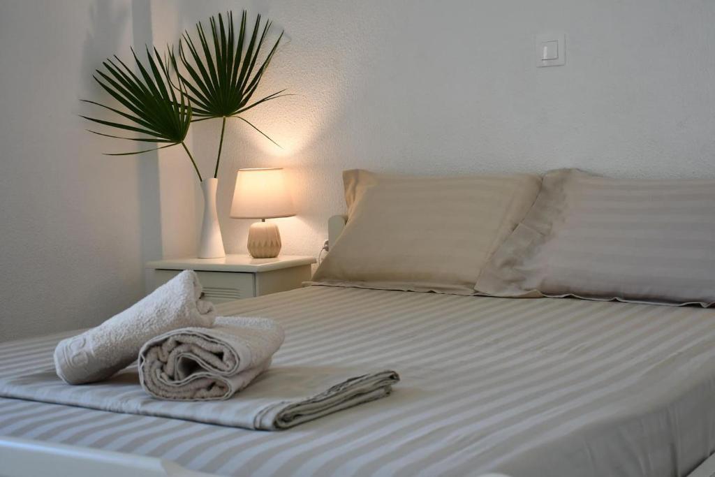 uma cama branca com toalhas e uma planta em Central flat, 300m from the beach em Lerápetra