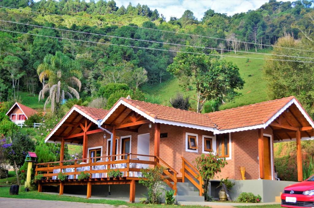 a house with a balcony in front of a mountain at Chalés Fazenda Vale da Mata in Monte Verde