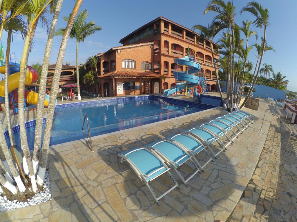 a swimming pool with a blue chair and a blue bench in front of it at Hotel Marazul in Cananéia