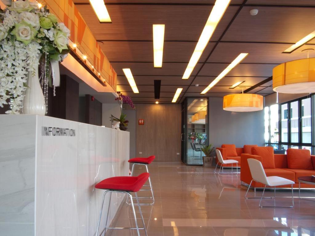 a lobby with orange chairs and tables in a building at ABIZZ Hotel Lampang Airport in Lampang