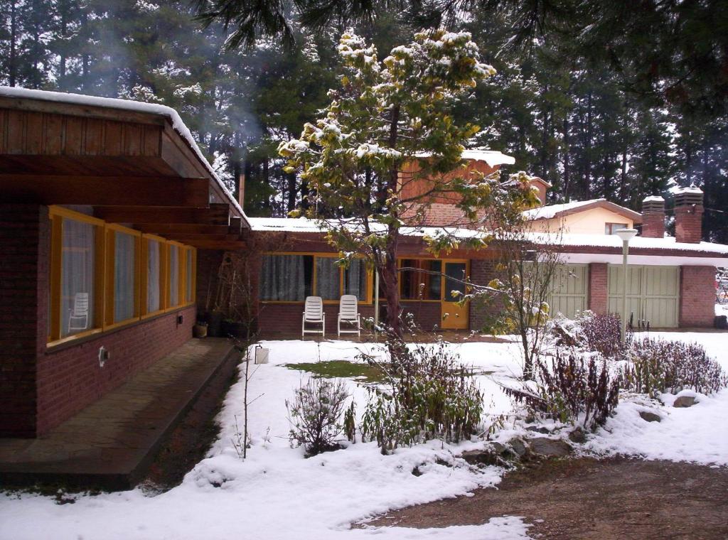 una casa con nieve en el suelo delante de ella en Hosteria La Chacra en Esquel