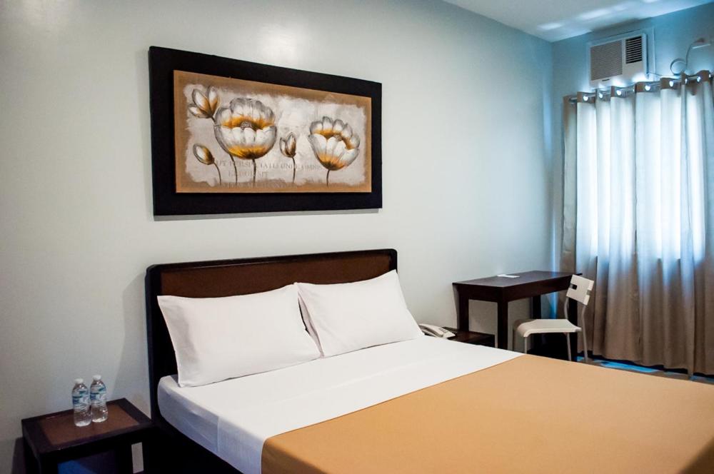 a bedroom with a bed and a table with a chair at Seasons Hotel Sablayan in Buenavista