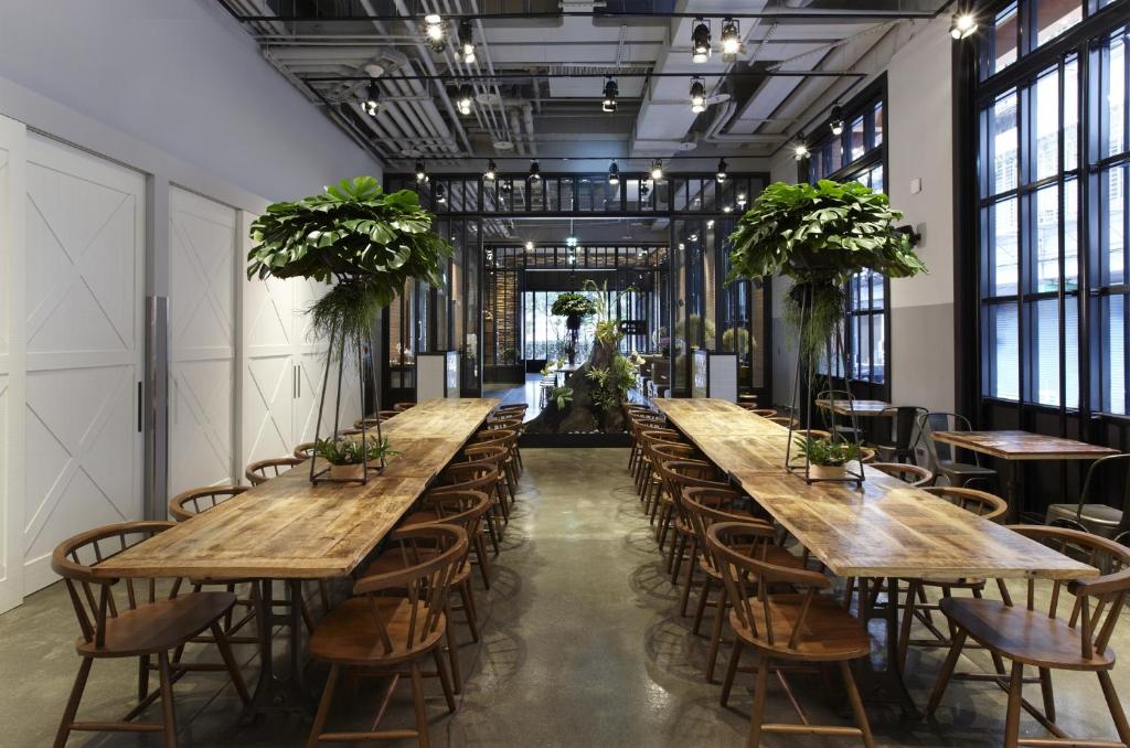 a row of tables in a room with chairs and plants at Just Sleep - Sanchong in Taipei