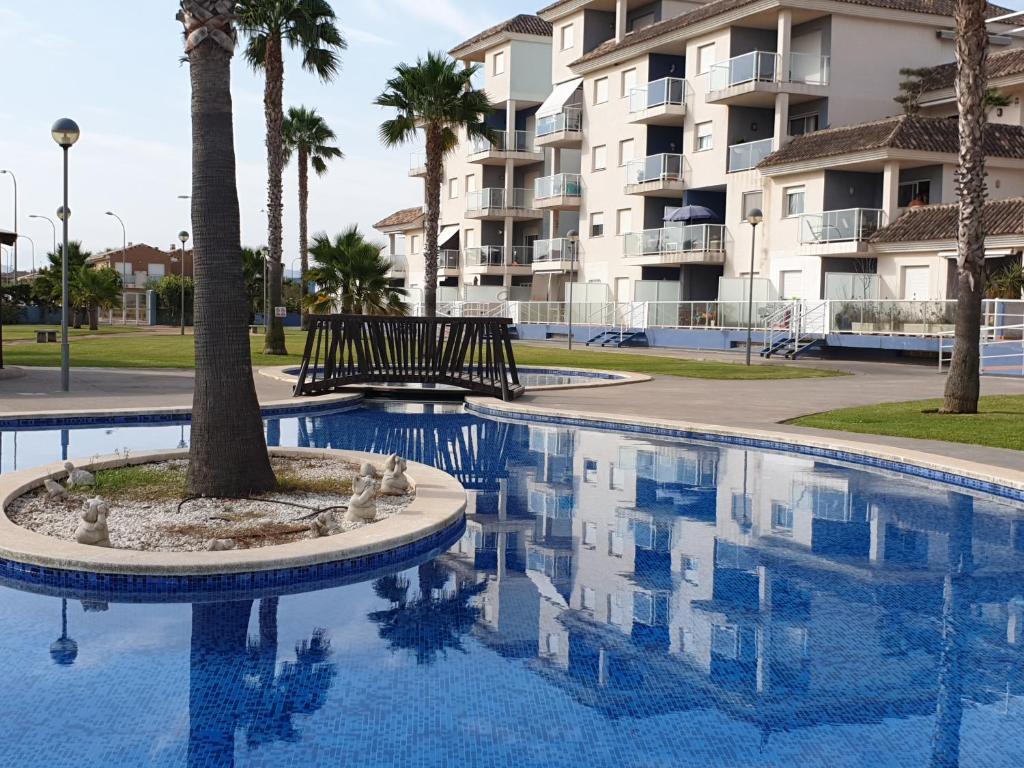 une piscine avec un palmier en face d'un bâtiment dans l'établissement AguaBlanca 1km playa Deveses, à El Verger