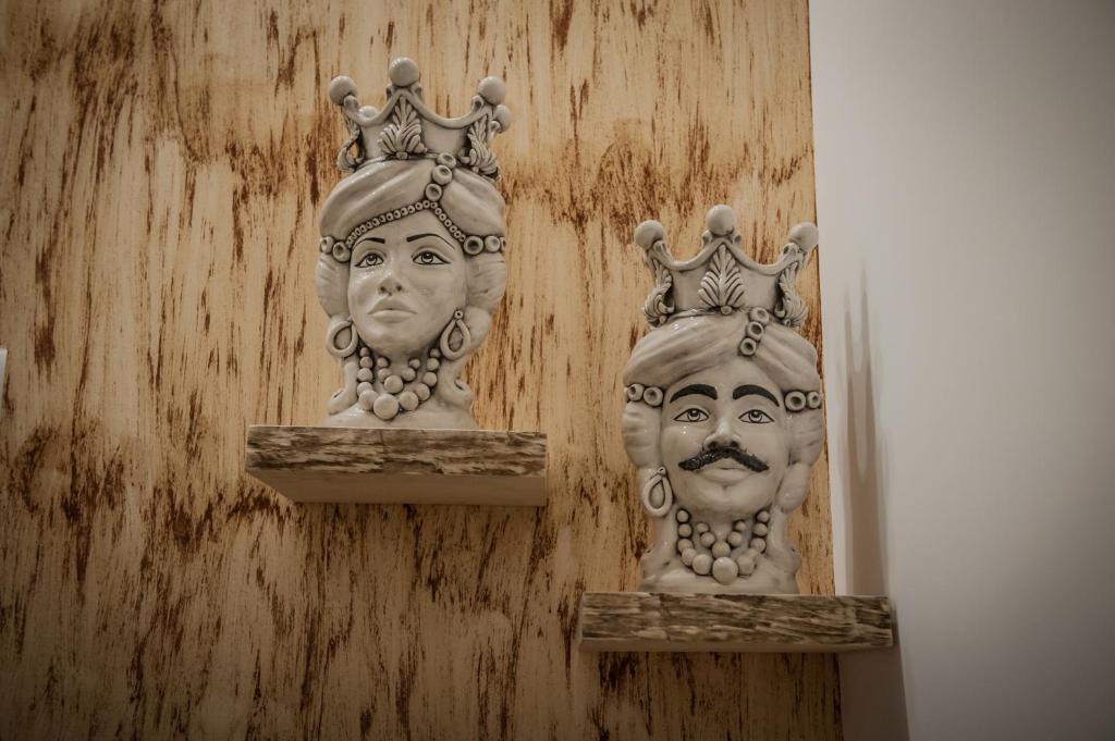 dos estatuas de cabezas con coronas en una pared en B&B iMori, en Caltagirone