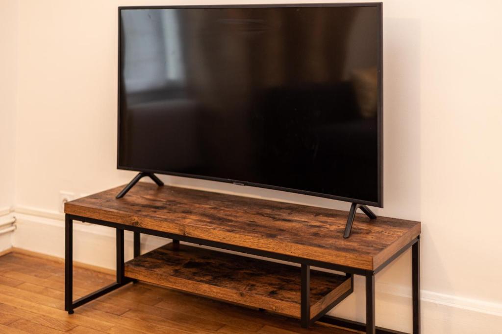 a flat screen tv sitting on a wooden tv stand at Proche Paris, Confort, Wifi, Netflix in Deuil-la-Barre