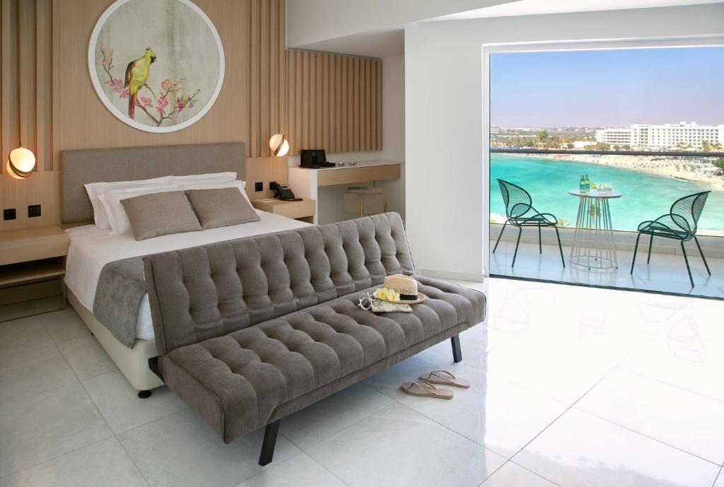 a bedroom with a large bed and a couch at NissiBlu Beach Resort in Ayia Napa