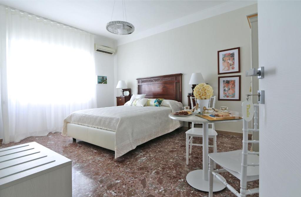 a white bedroom with a bed and a table at SOLIDEA BNB in Salerno