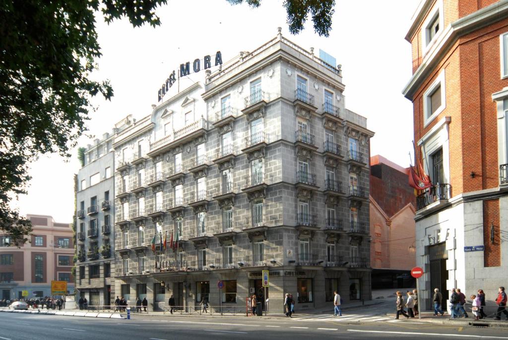 un grand bâtiment sur une rue de la ville avec des gens debout autour de celle-ci dans l'établissement Hotel Mora by MIJ, à Madrid