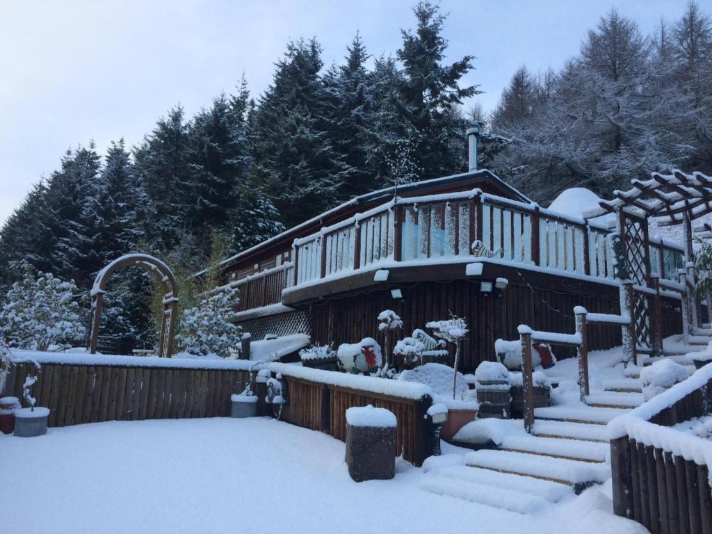 Ramintoul Lodge في Glendevon: منزل مغطى بالثلج مع السلالم والأشجار