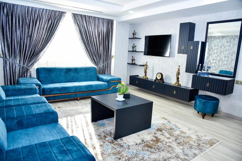 a living room with blue couches and a tv at Supreme Hotel Baku in Baku