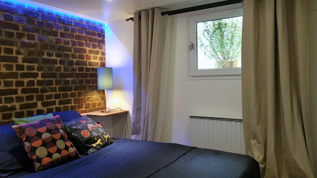 a bedroom with a brick wall and a bed at DOUX COCON DE 50 m2 PARIS-LE RAINCY in Le Raincy