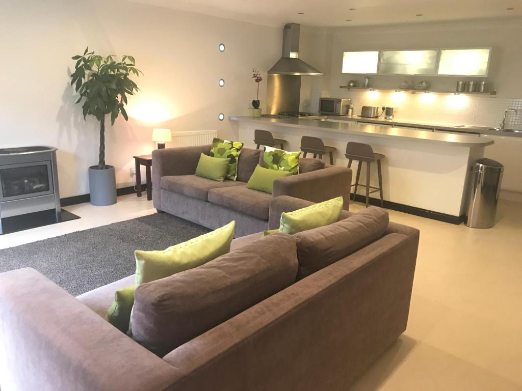a living room with two couches and a kitchen at Aaron Glen Apartments in Edinburgh