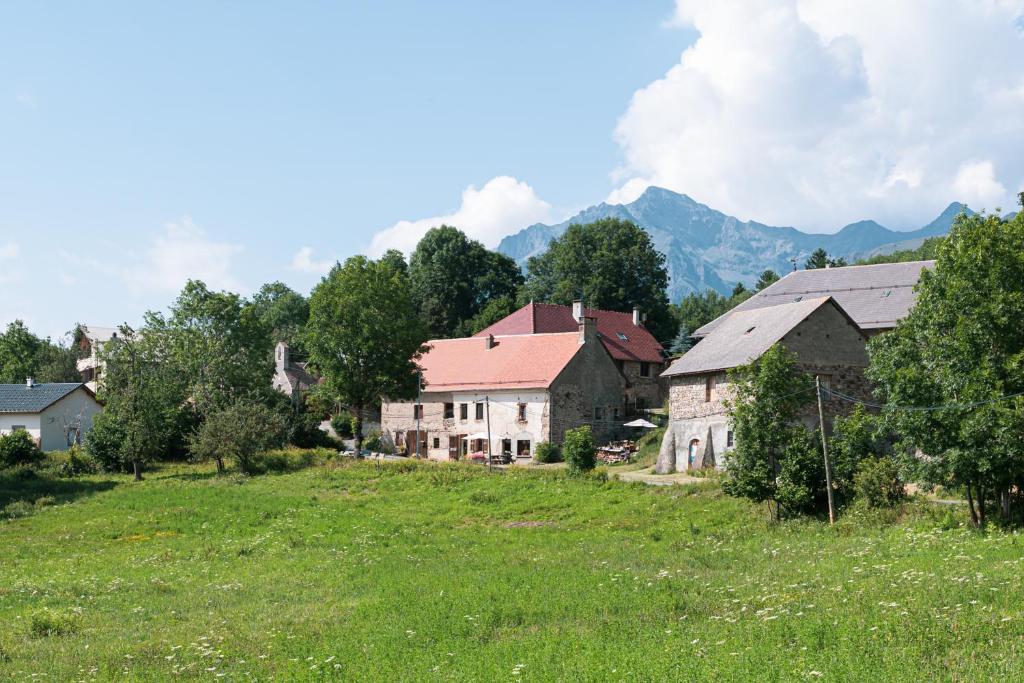 un groupe de maisons dans un champ avec des montagnes en arrière-plan dans l'établissement B&B MaisonNel, à Saint-Bonnet-en-Champsaur