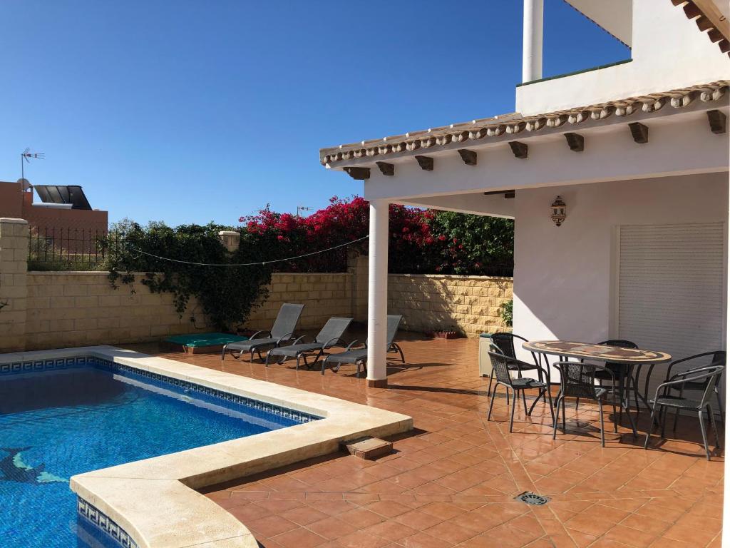 a swimming pool with chairs and a table next to a house at Casa de la Colina in Torre del Mar