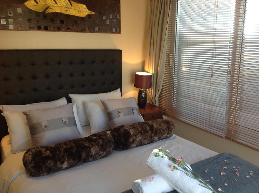 a bedroom with a large bed with pillows on it at Secret Garden Guesthouse in Bloubergstrand