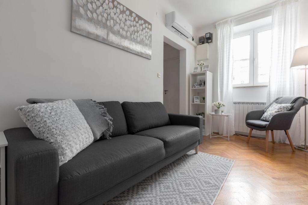 ein Wohnzimmer mit einem schwarzen Sofa und einem Stuhl in der Unterkunft City Center Pearl 2 in Zagreb