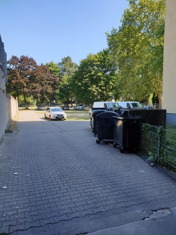 una strada con bidoni della spazzatura e una macchina parcheggiata sopra di Workers-Sleep-Station a Colonia