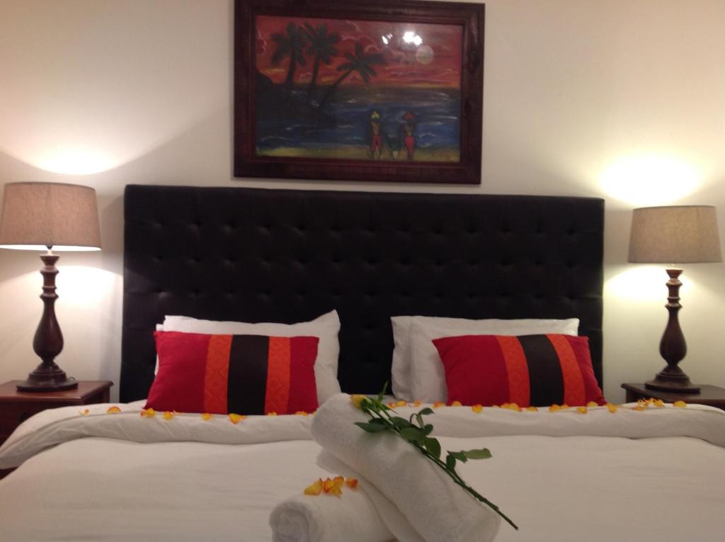 a bedroom with two beds with red and black pillows at Secret Garden Guesthouse in Bloubergstrand