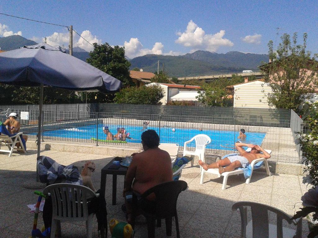 un grupo de personas sentadas en una mesa junto a una piscina en Camping Piano Grande, en Baveno