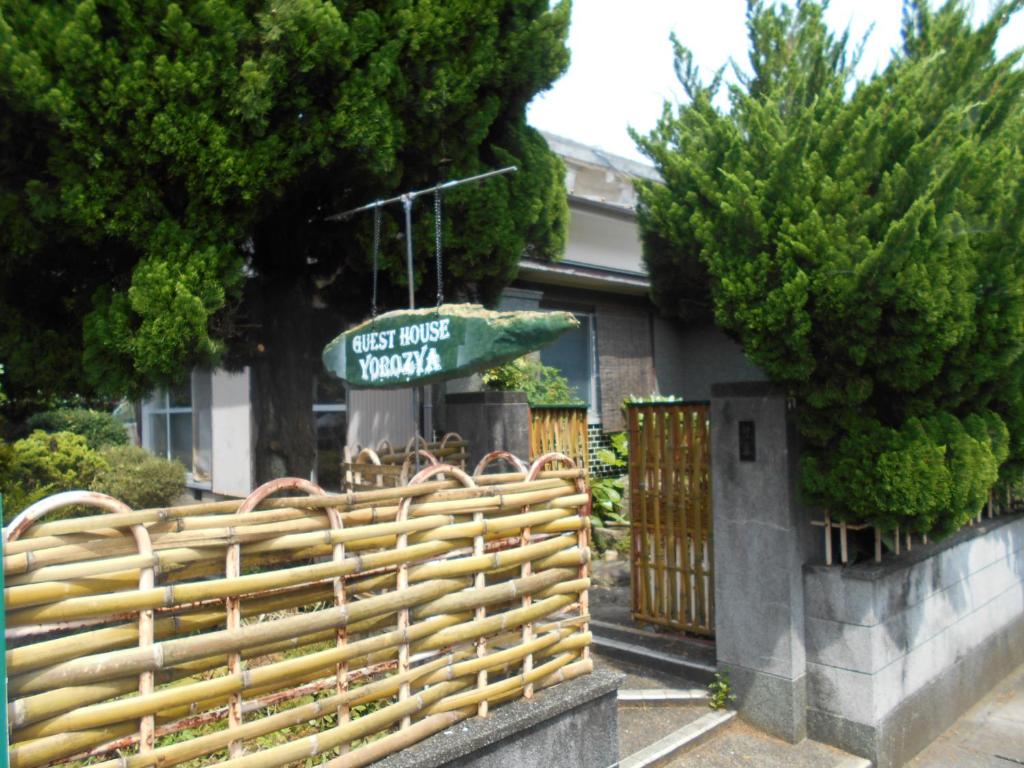 a fence with a sign in front of a house at ゲストハウスよろずや in Nahari