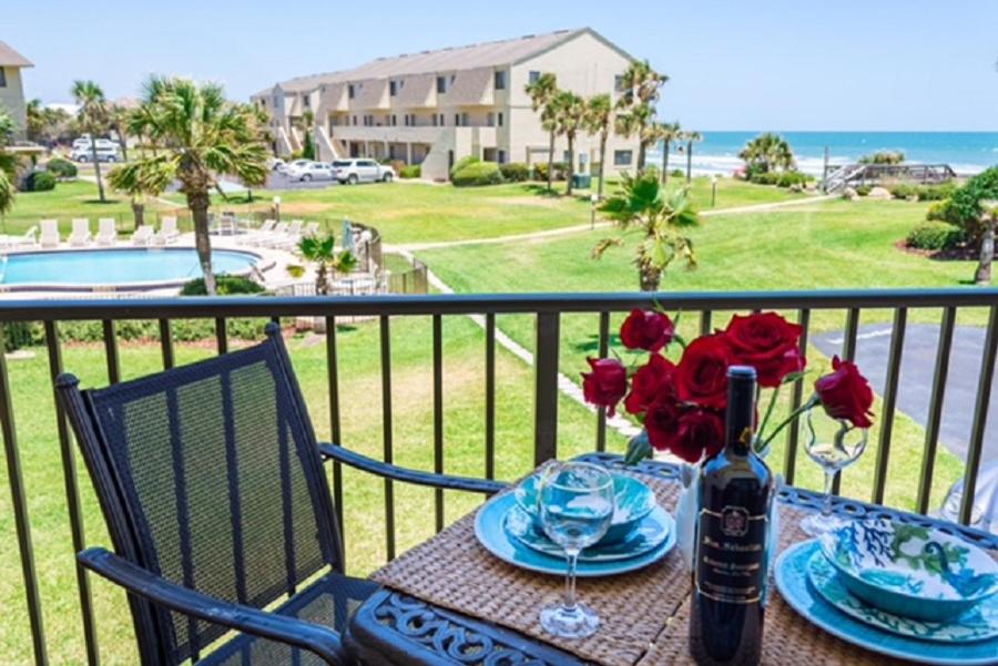 una mesa con una botella de vino y flores en el balcón en Summerhouse 251 Condo, en St. Augustine