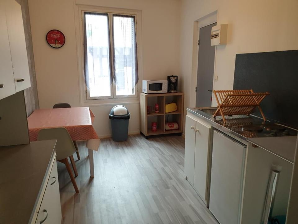 a room with a kitchen with a table and a microwave at appartement tiago in Le Tréport