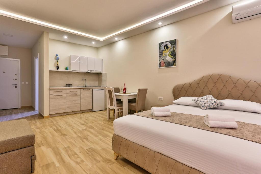 a bedroom with a bed and a table and a kitchen at Apolon Apart in Bar, Susanj
