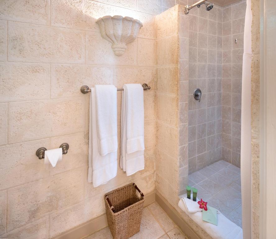 a bathroom with a shower and a toilet and towels at Little Arches Boutique Hotel - Adults Only in Christ Church