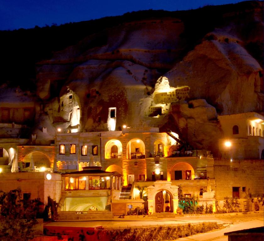a building is lit up at night in front of a mountain at Miras Hotel in Göreme