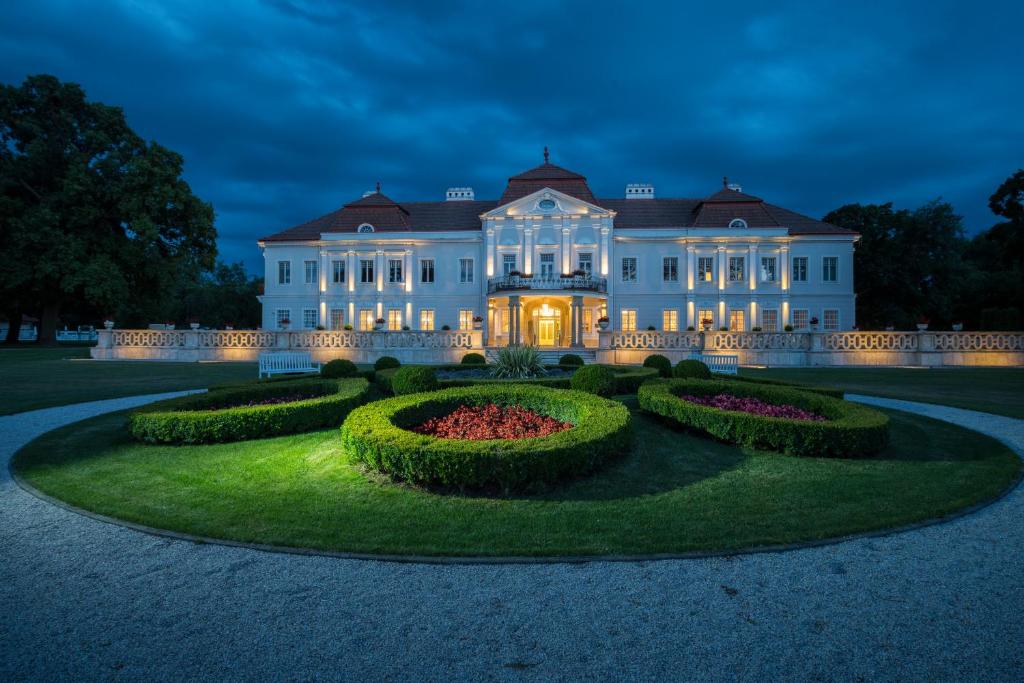 uma grande mansão branca com um jardim à noite em Art Hotel Kaštieľ em Tomášov