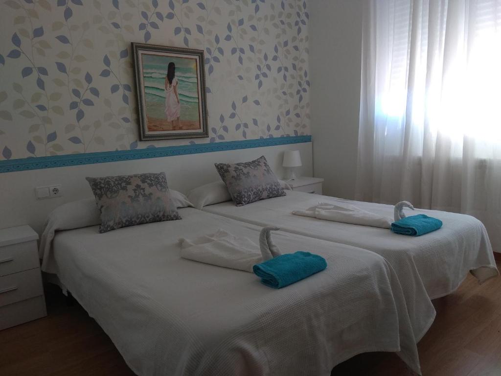 two beds in a bedroom with blue pillows on them at Hostal Caminito in La Bañeza