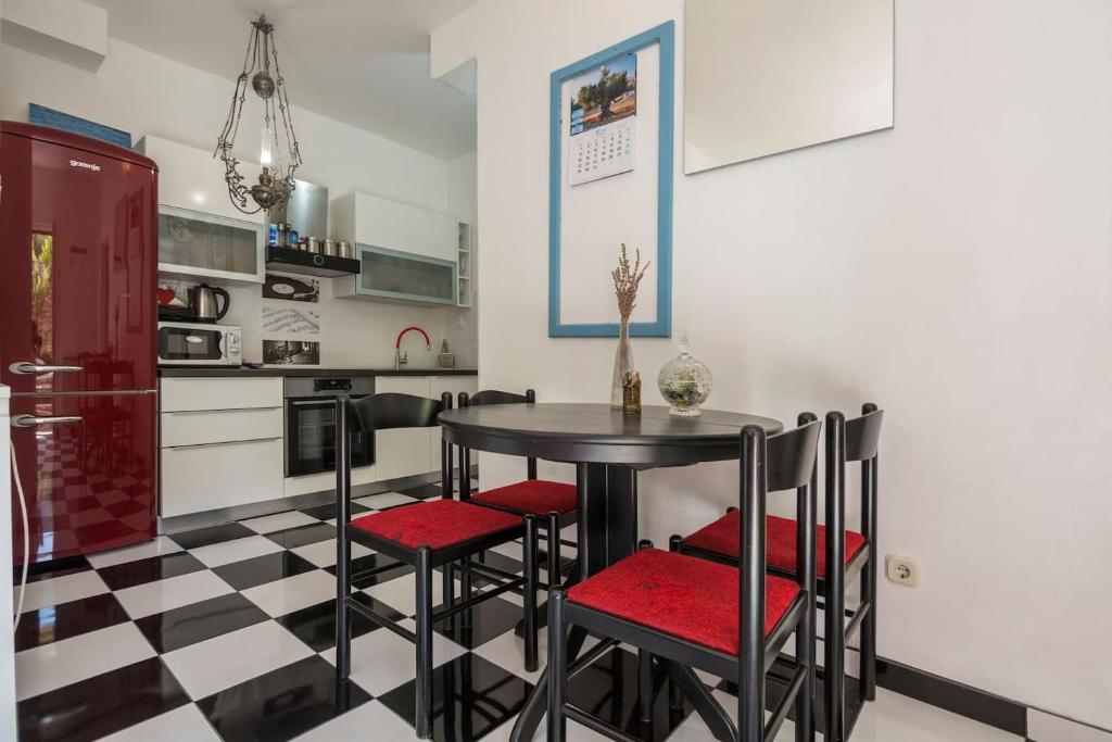 une cuisine avec une table noire et des chaises rouges dans l'établissement Black and White chill out, à Komiža