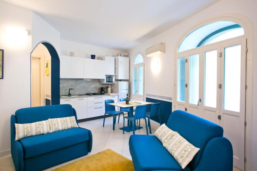 a living room with two blue chairs and a kitchen at BELLAGIO SUN pool near lake free parking in Bellagio