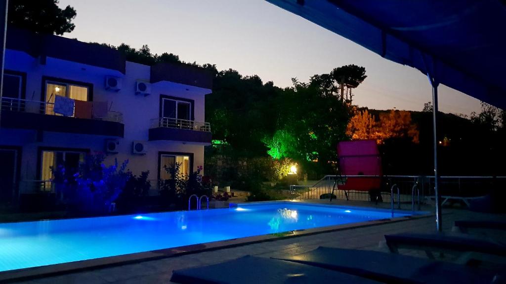 a swimming pool in front of a house at night at Rose Pension in Patara