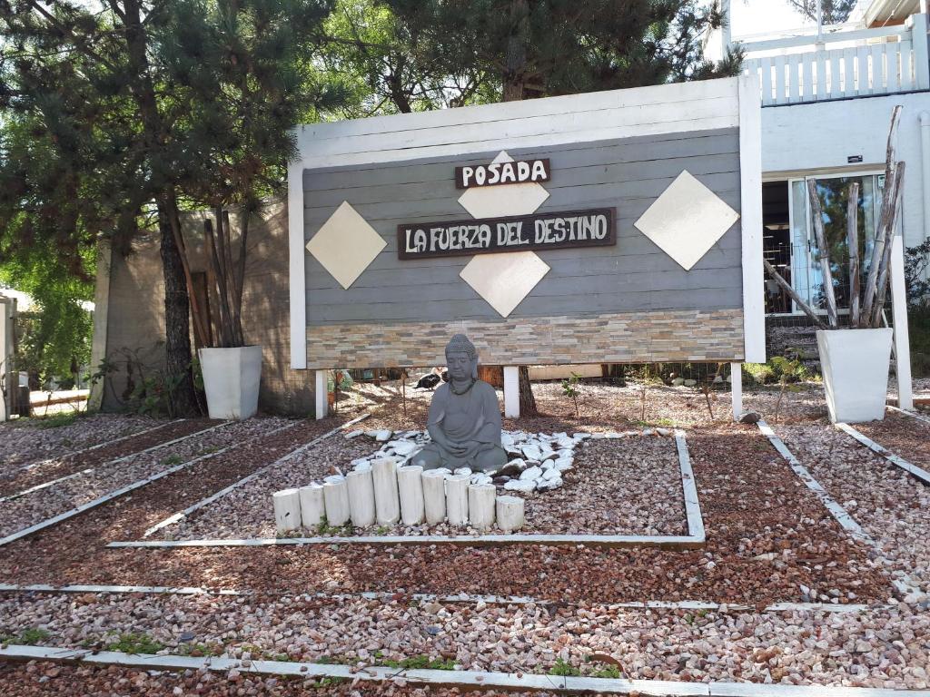 a statue sitting in front of a sign at La Fuerza Del Destino in Piriápolis