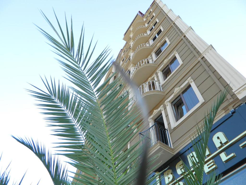 a tall building with a palm tree in front of it at Hotel Iberia in Batumi