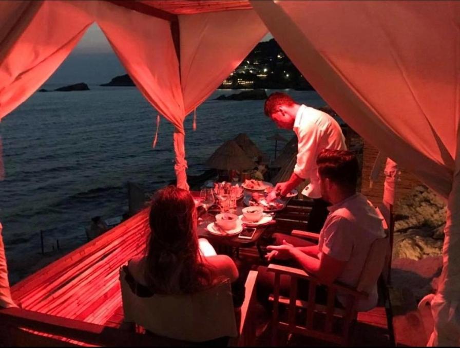 a group of people sitting at a table near the ocean at Guesthouse DONA in Ulcinj