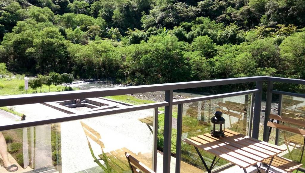 einen Balkon mit einer Bank und Parkblick in der Unterkunft Antong Creekside Hot Spring in Yuli