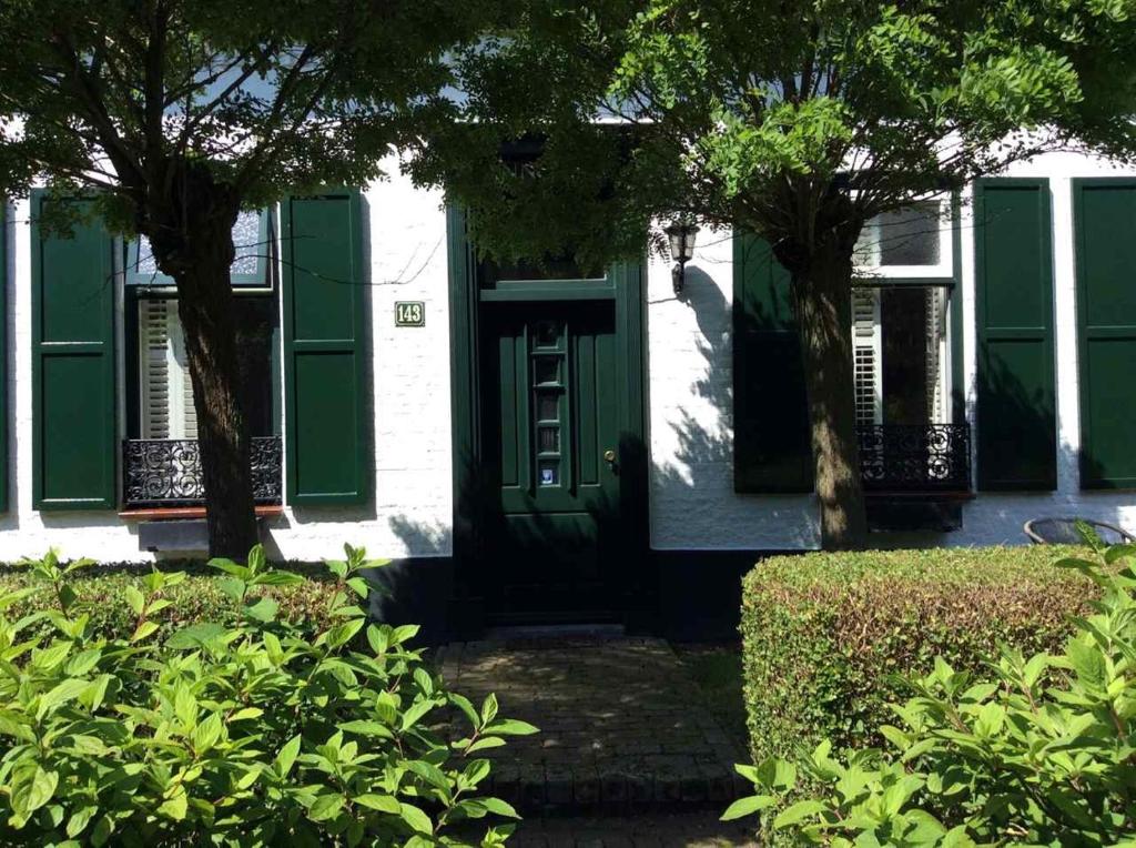 a green door on a white house with trees at B&B de Tol in Hulst