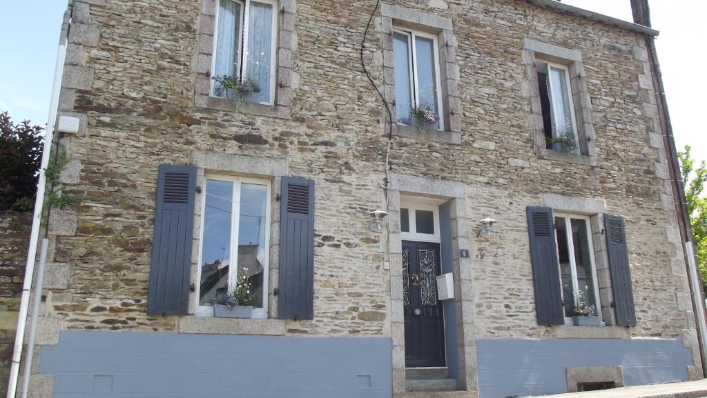 un edificio de ladrillo con puertas y ventanas azules en Maison Jonela, en Châteauneuf-du-Faou