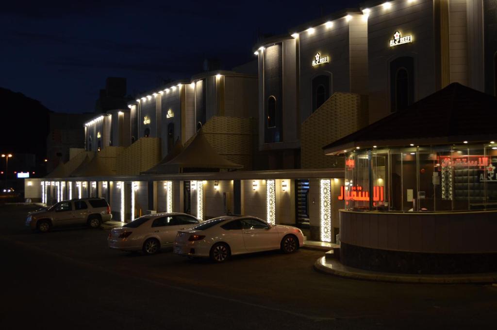 zwei Autos, die vor einem Gebäude mit Lichtern geparkt sind in der Unterkunft Alreef Diamond Villas in Ta'if