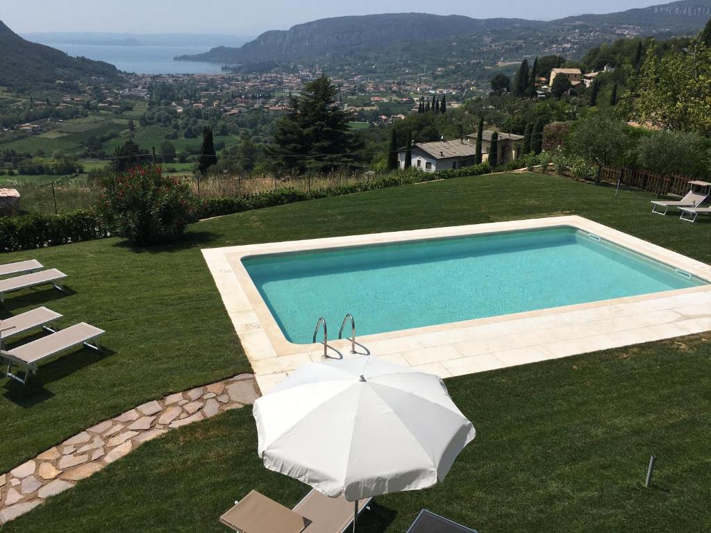 a swimming pool with an umbrella and chairs at BellaVista Relax - Adults Only in Costermano