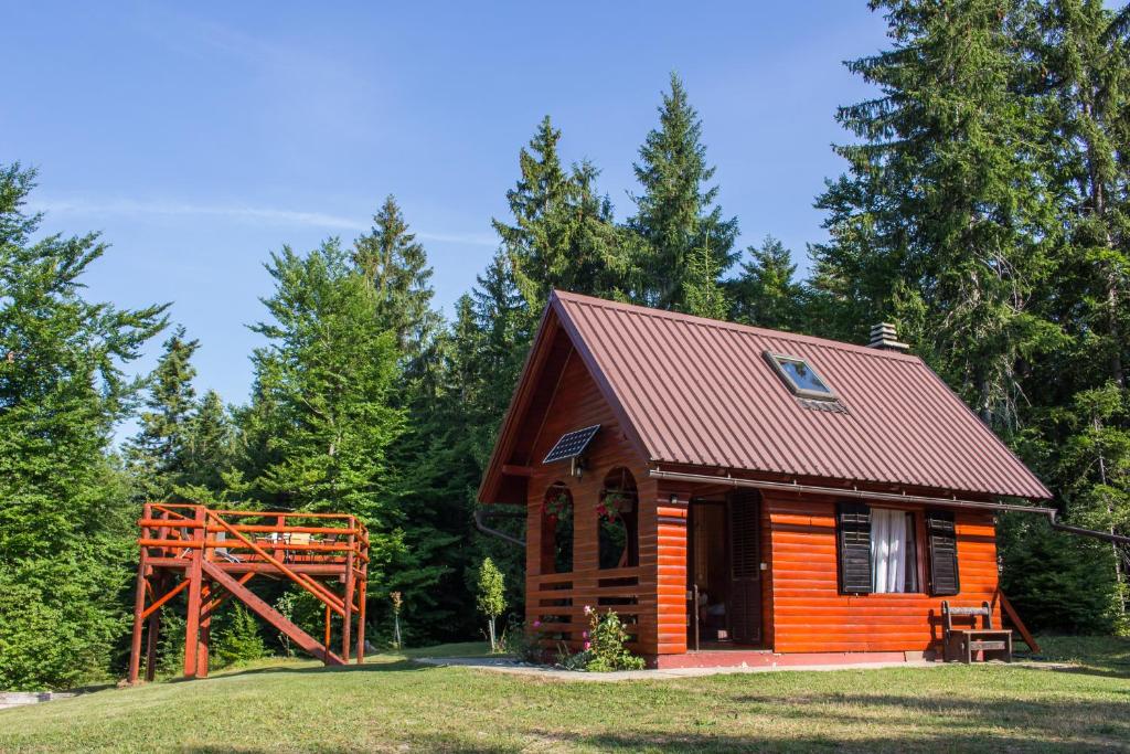 a small cabin in the woods with a red roof at Robinzonski smještaj Gak - Medo in Čabar