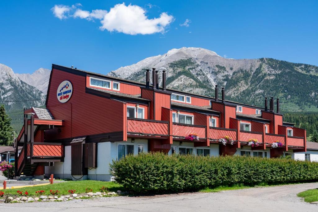 a large red building with mountains in the background at Rocky Mountain Ski Lodge in Canmore